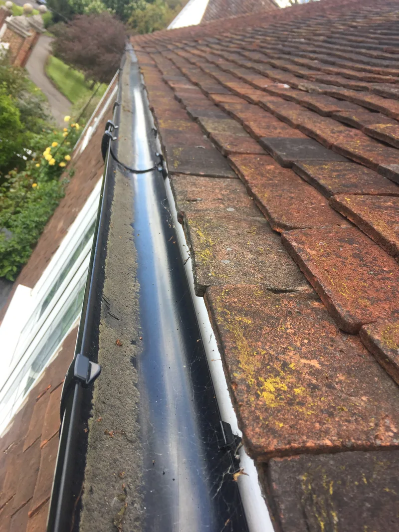 Clear black round-line gutter beneath red roof tiles