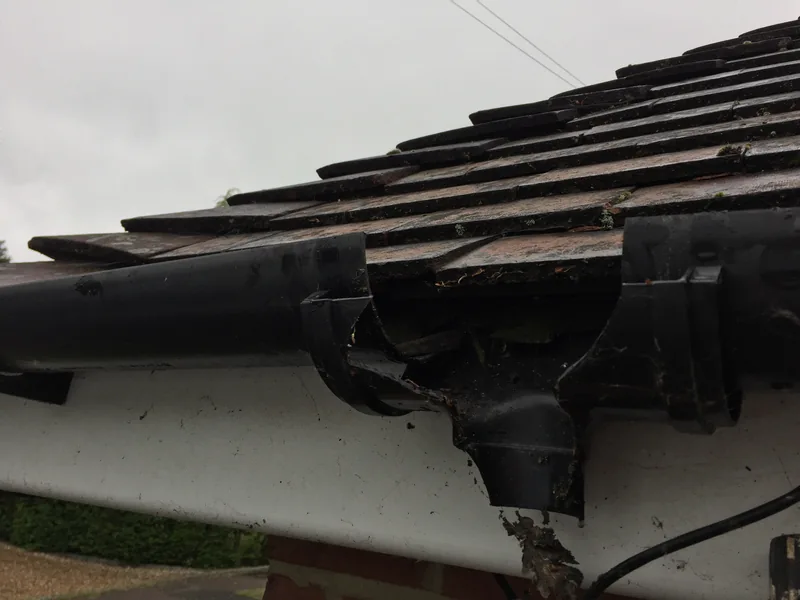 Broken black running outlet with sections missing around the gutter joint