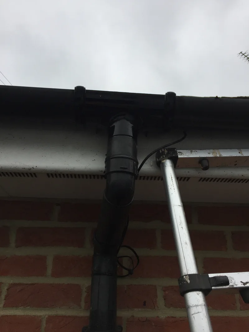 Intact black running outlet and connected downpipe beneath a white fascia