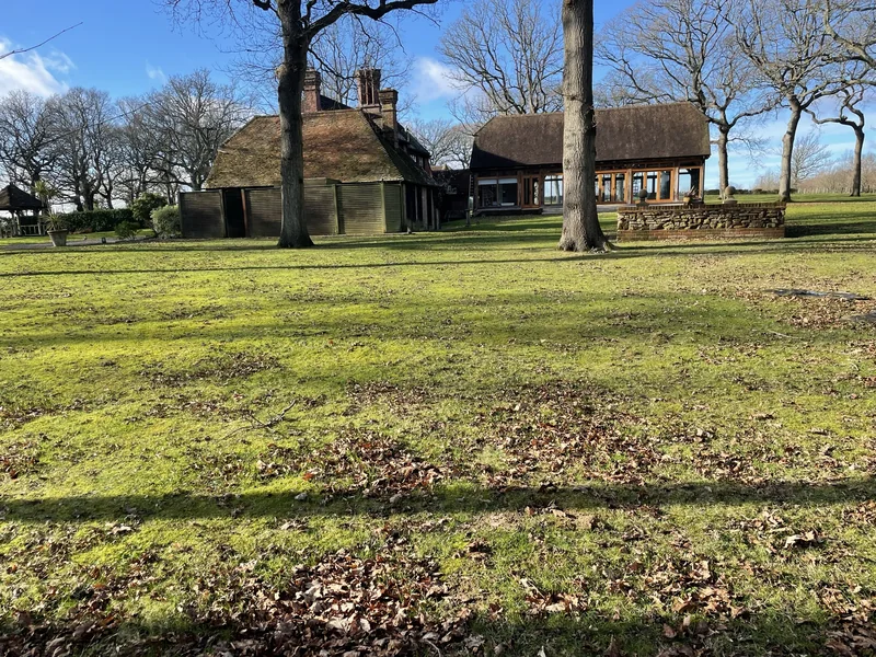 Traditional tiled-roof property beyond a lawn and mature trees