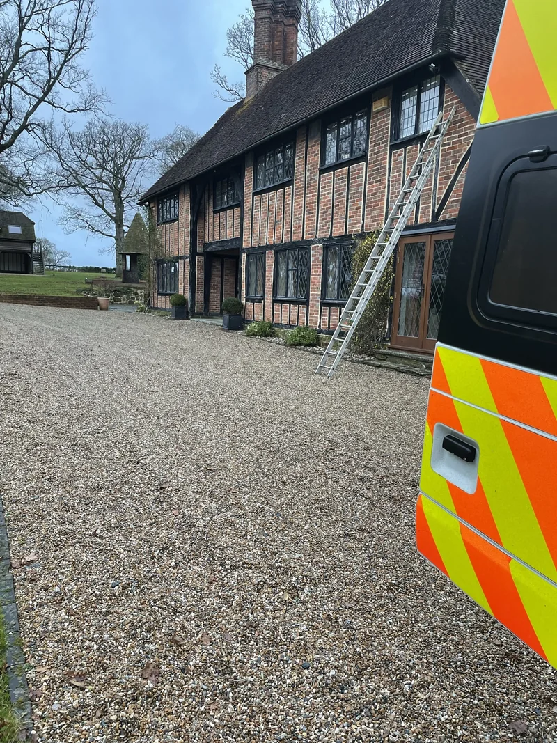 Timber-framed house with a ladder against the elevation and a work vehicle in the foreground